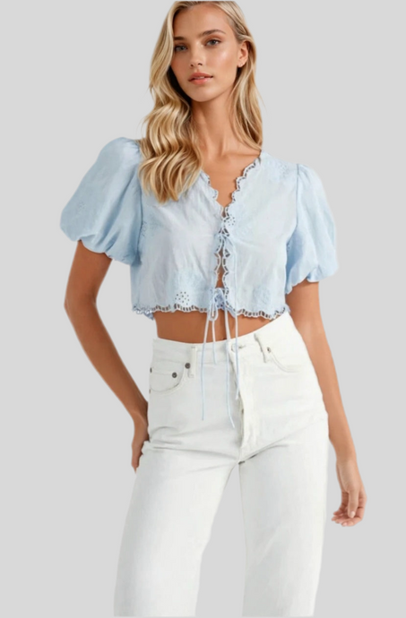 Light blue puff sleeve crop top with lace-up front and scalloped hem, styled with high-waisted white jeans.