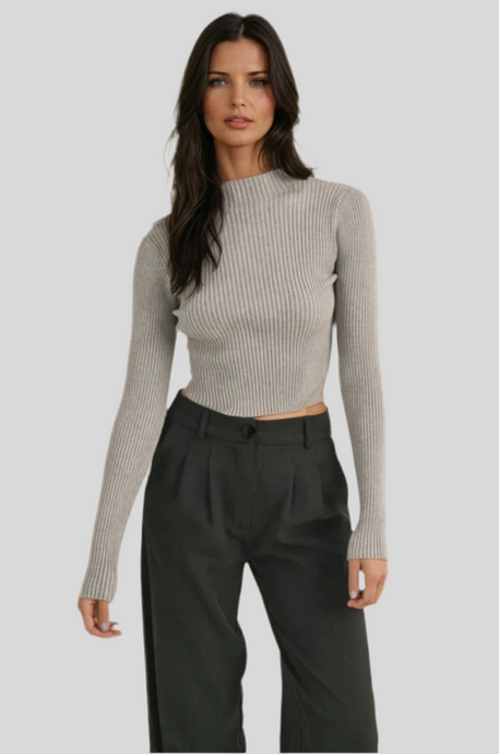Women’s ribbed knit long sleeve sweater in grey, cropped fit, mock neck, paired with high-waist black trousers.