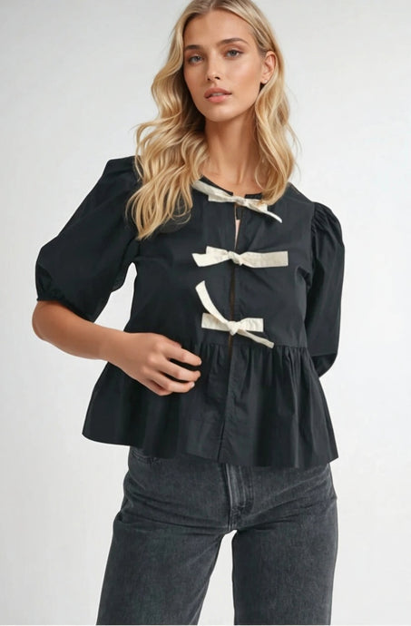 Black puff sleeve blouse with black bow tie accents, made from 100% rayon, styled with light blue jeans.