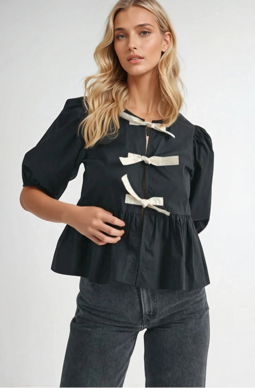 Black puff sleeve blouse with black bow tie accents, made from 100% rayon, styled with light blue jeans.